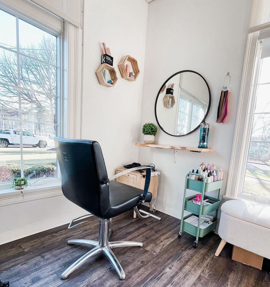 Bright salon suite styling station with a round mirror and color cart beside large windows at H2T Salon & Spa in Foxborough, MA showcasing how salon google reviews build to suite ownership.